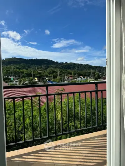 Scenic balcony view with lush greenery and distant hills under a clear blue sky.