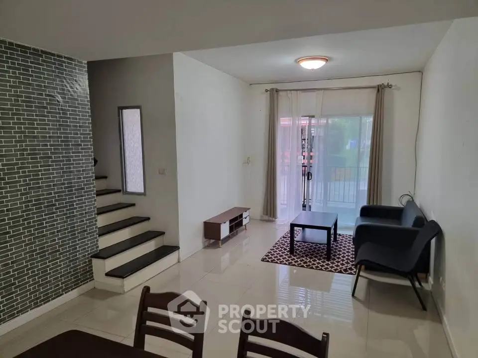 Spacious living room with modern staircase and natural light, perfect for family gatherings.