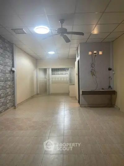 Spacious interior with tiled flooring and ceiling fan, ideal for versatile living space.
