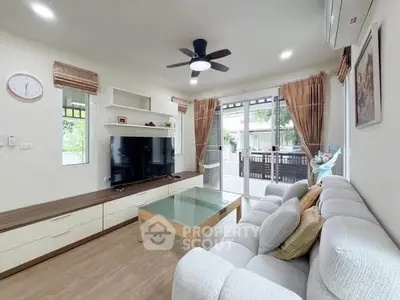Spacious living room with modern decor and large windows opening to a balcony.
