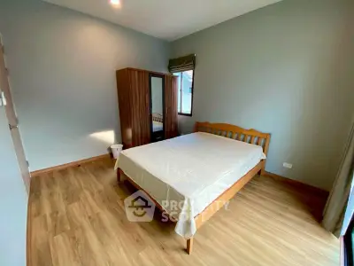 Spacious bedroom with wooden flooring and modern furnishings in a cozy apartment.