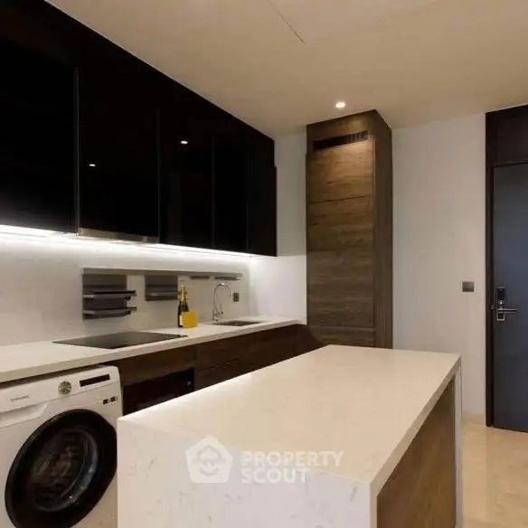 Modern kitchen with sleek design, featuring a washing machine and stylish cabinetry.