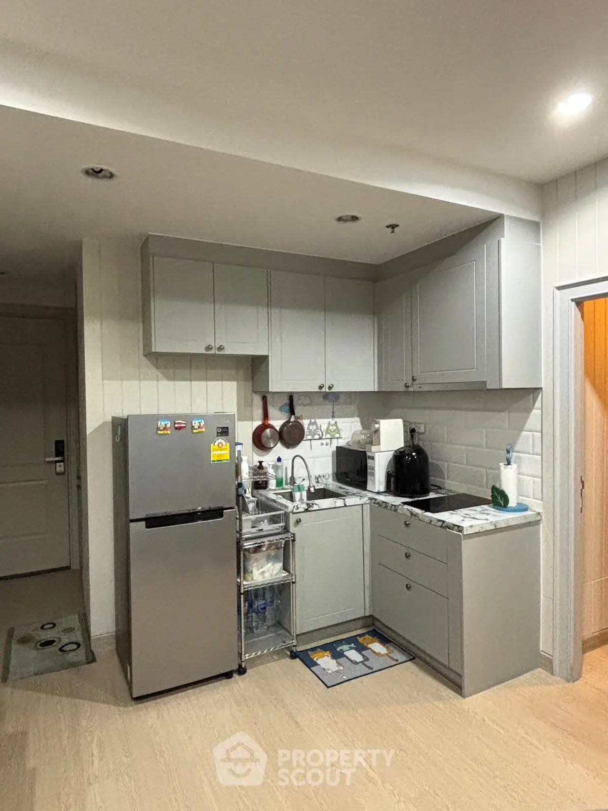 Modern compact kitchen with sleek gray cabinets and stainless steel fridge