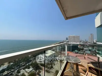 Stunning ocean view from high-rise balcony with modern glass railing and outdoor seating.