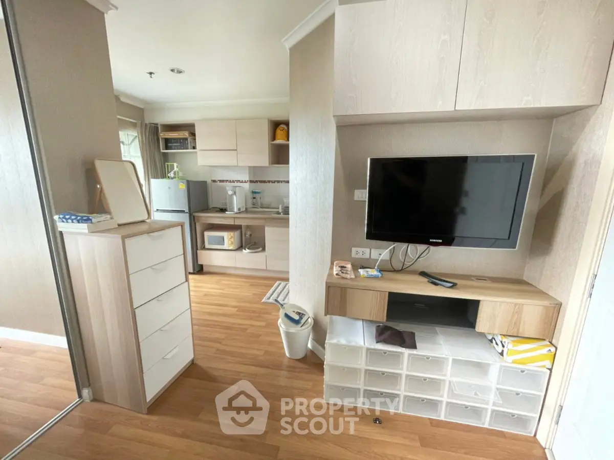 Modern apartment interior with open kitchen and living area, featuring wooden flooring and built-in storage.