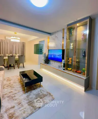 Luxurious modern living room with elegant decor and open dining area, featuring sleek furniture and ambient lighting.