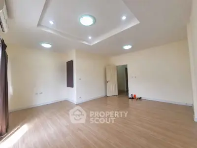 Spacious empty room with modern ceiling lights and wooden flooring, perfect for customization.