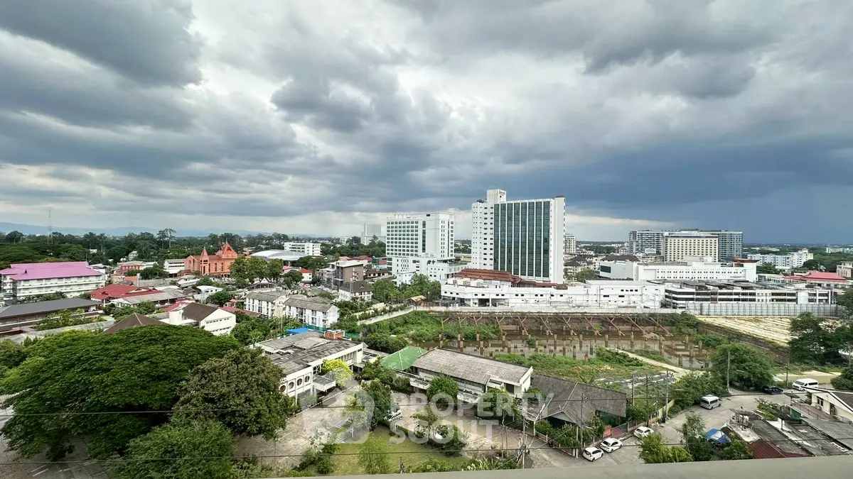 Stunning cityscape view with modern buildings and lush greenery under dramatic cloudy skies.
