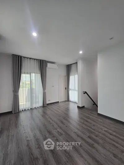 Spacious modern living room with elegant flooring and large windows for natural light.