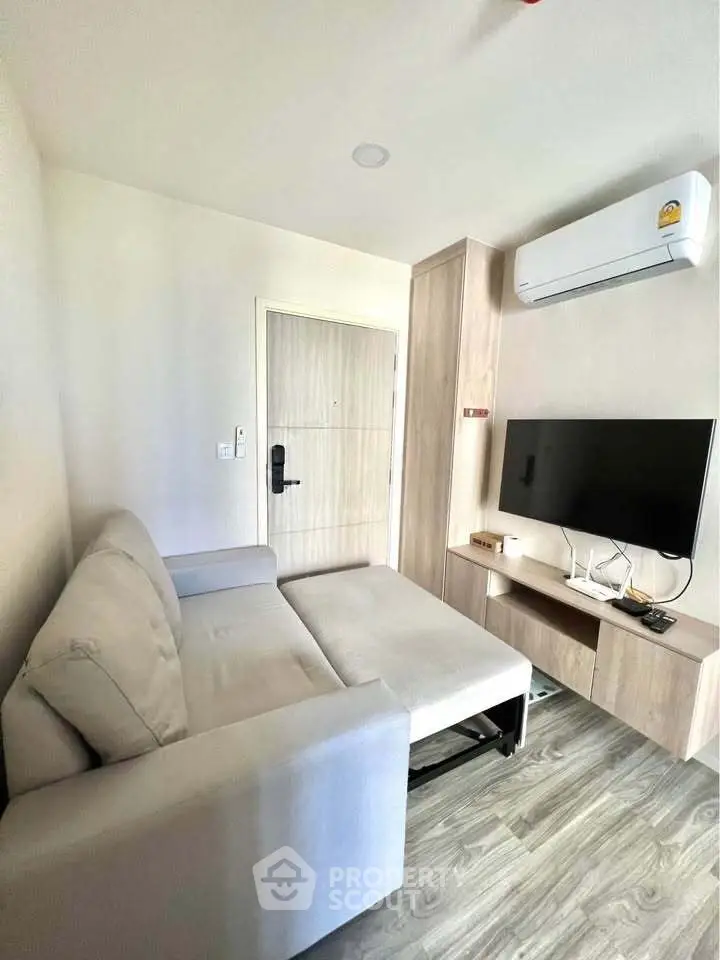 Modern living room with sleek furniture and wall-mounted TV, featuring a cozy sofa and air conditioning.