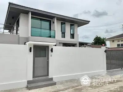 Modern two-story house with sleek design and large windows in a suburban neighborhood.