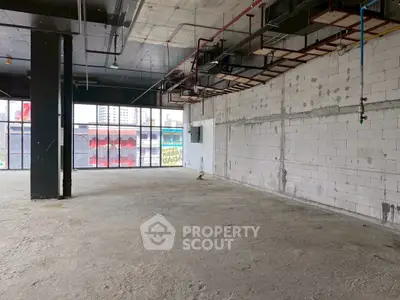 Spacious unfinished commercial space with large windows and exposed ceiling pipes.