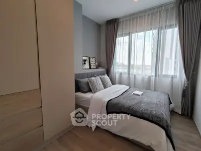 Modern bedroom with stylish decor and large window offering natural light.