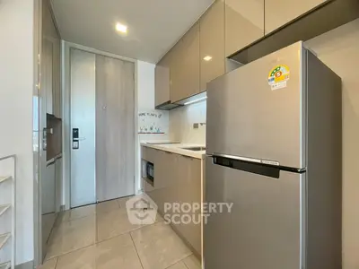 Modern kitchen with sleek cabinetry and stainless steel fridge in contemporary apartment.