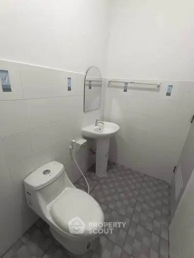 Compact bathroom with modern fixtures and tiled flooring, ideal for efficient space utilization.