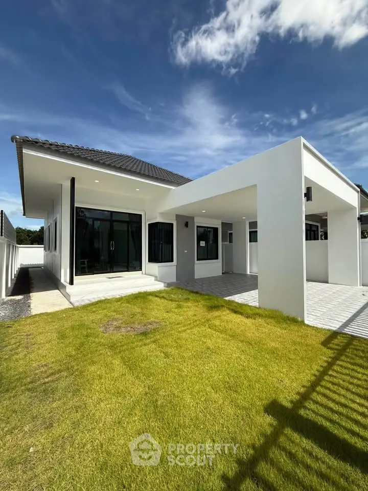 Modern single-story house with sleek design and spacious lawn under a clear blue sky.