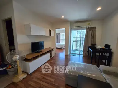 Modern living room with wooden flooring and natural light, featuring a cozy sofa and entertainment unit.