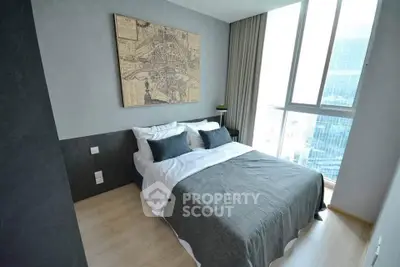 Modern bedroom with large window and city view, featuring stylish decor and cozy bedding.