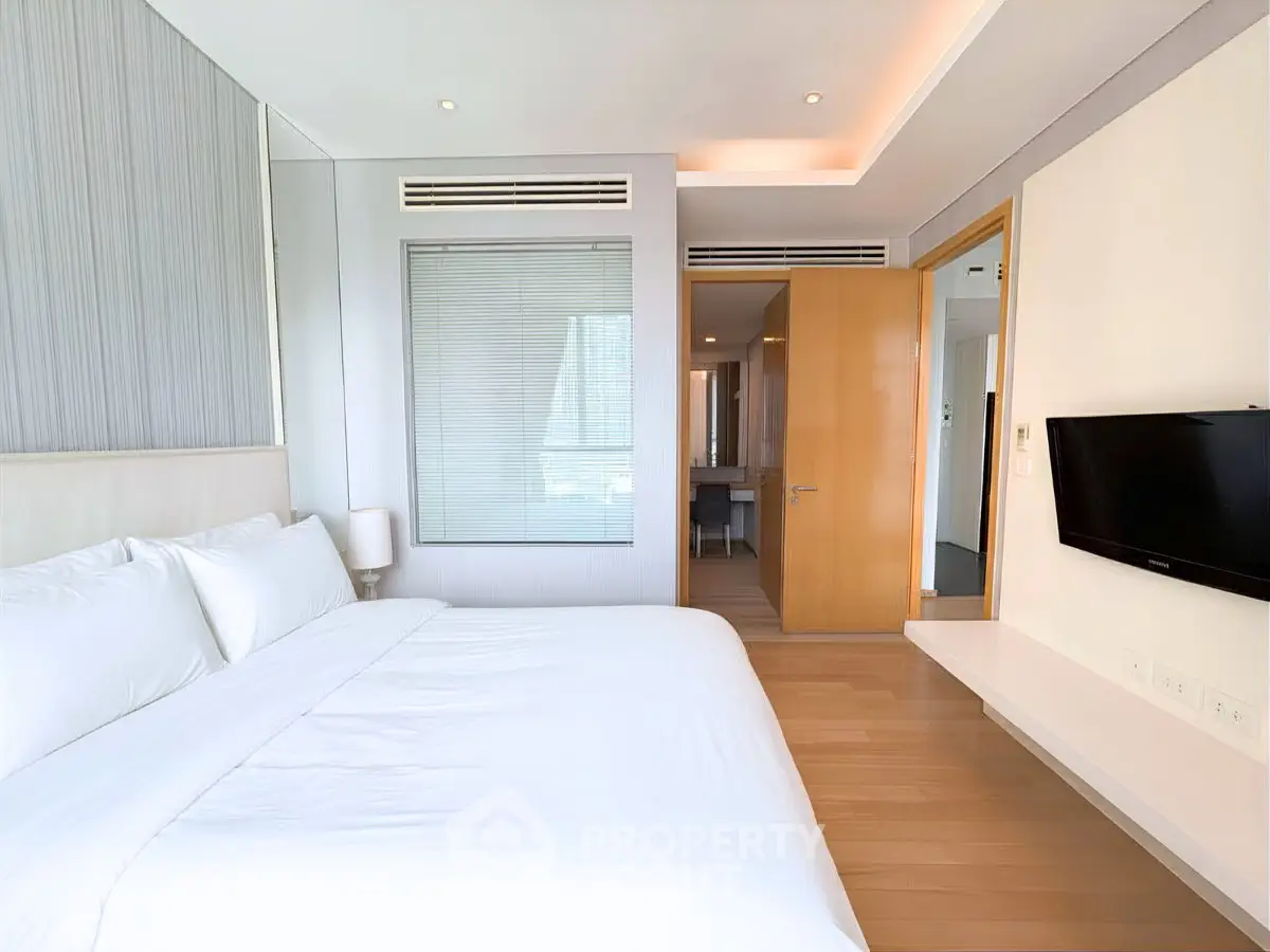 Luxurious modern bedroom with sleek design and ambient lighting, featuring a wall-mounted TV and elegant decor.