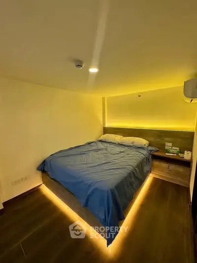 Cozy bedroom with modern lighting and wooden flooring, perfect for relaxation.