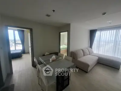 Modern apartment with open living and dining area, featuring large windows and natural light.