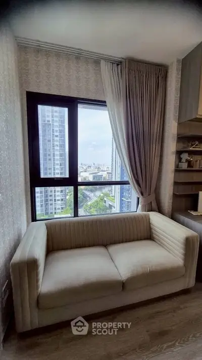 Cozy living room with a plush sofa and a stunning city view from the window.