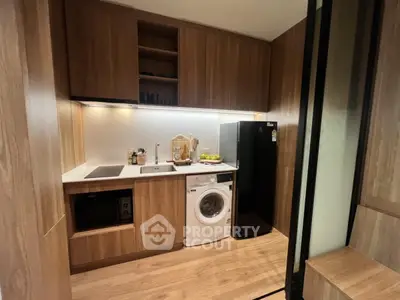 Modern kitchen with wooden cabinets, washing machine, and sleek appliances