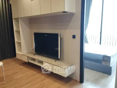 Modern living room with sleek TV unit and view into cozy bedroom