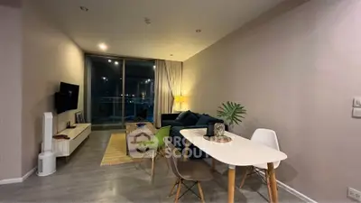 Modern living room with stylish furniture and large window offering stunning night view.