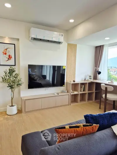 Modern living room with sleek furniture and large TV, featuring a stylish air conditioner and cozy decor.
