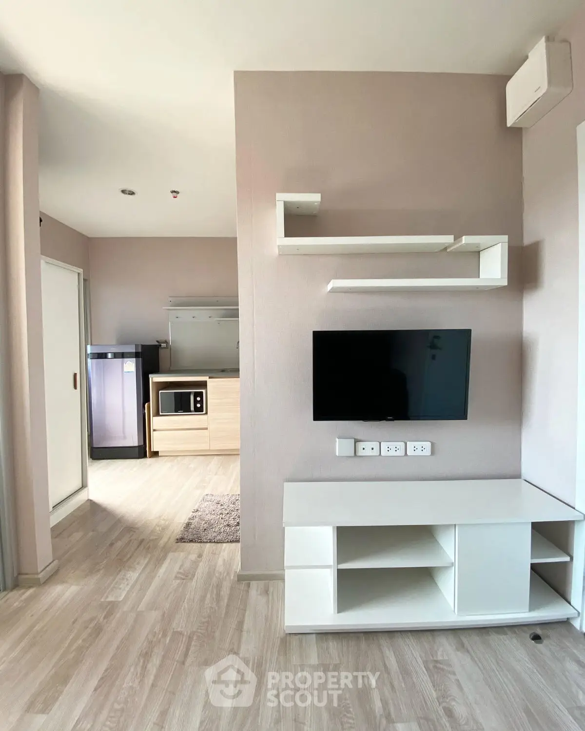 Modern living room with sleek TV setup and open kitchen layout in stylish apartment.