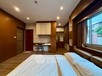 Spacious bedroom with modern wooden accents and large window for natural light.