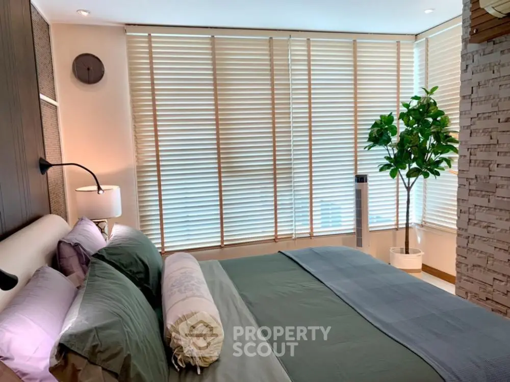 Luxurious bedroom with modern decor and large windows with blinds.