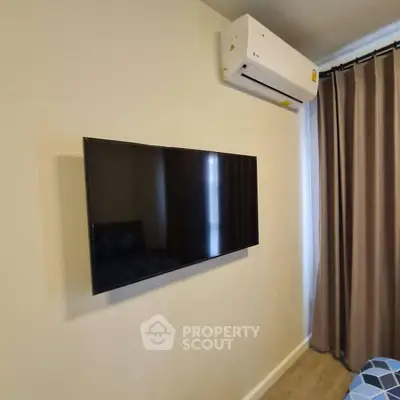 Modern bedroom with wall-mounted TV and air conditioning unit, featuring stylish curtains.