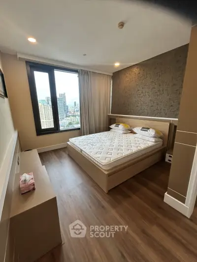 Modern bedroom with city view, featuring wooden flooring and stylish decor in a high-rise apartment.