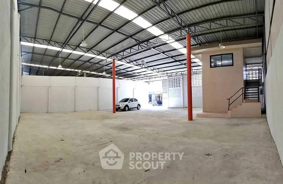Spacious industrial warehouse with high ceilings and ample parking space.