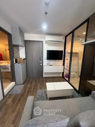 Modern living room with sleek design, featuring a wall-mounted TV, stylish furniture, and wooden flooring.