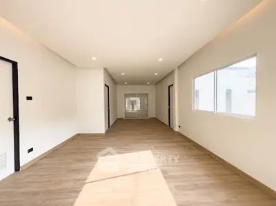 Spacious modern living room with large windows and wooden flooring, perfect for natural light lovers.