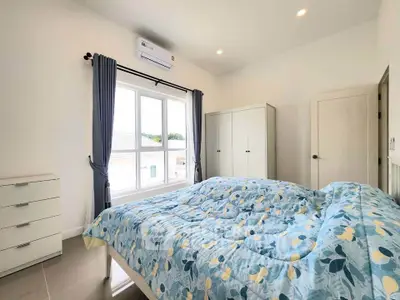 Bright and airy bedroom with large window and modern furnishings, perfect for a cozy retreat.