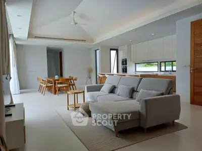 Spacious modern living room with open kitchen and dining area, featuring elegant furniture and natural light.