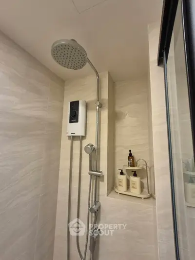 Modern bathroom with sleek showerhead and built-in shelf for toiletries.