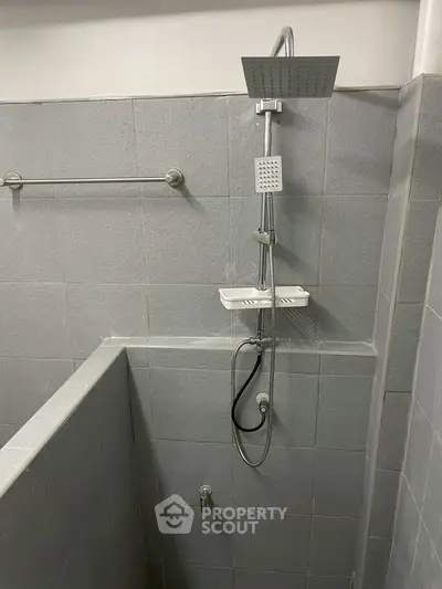 Modern bathroom with sleek gray tiles and a contemporary shower setup.