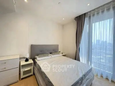 Modern bedroom with large window and city view, featuring elegant decor and natural light.