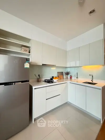 Modern kitchen with sleek cabinetry and stainless steel fridge in a contemporary apartment.