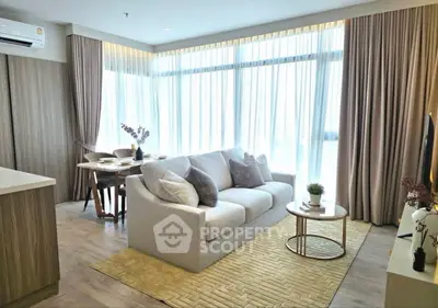 Modern living room with large windows, cozy sofa, and elegant decor in a bright apartment.