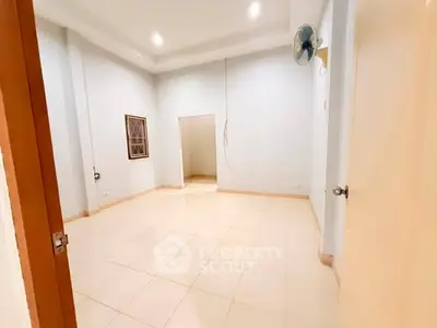 Spacious empty room with tiled flooring and ceiling fan, ready for customization.