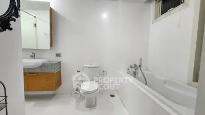 Modern bathroom with white tiles, bathtub, and sleek fixtures.