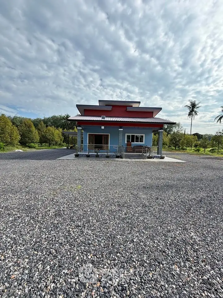 Charming countryside house with spacious gravel driveway and lush greenery, perfect for serene living.