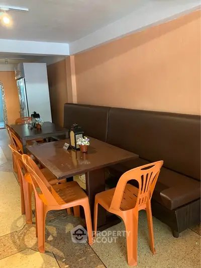 Cozy dining area with orange chairs and brown bench seating, perfect for casual gatherings.