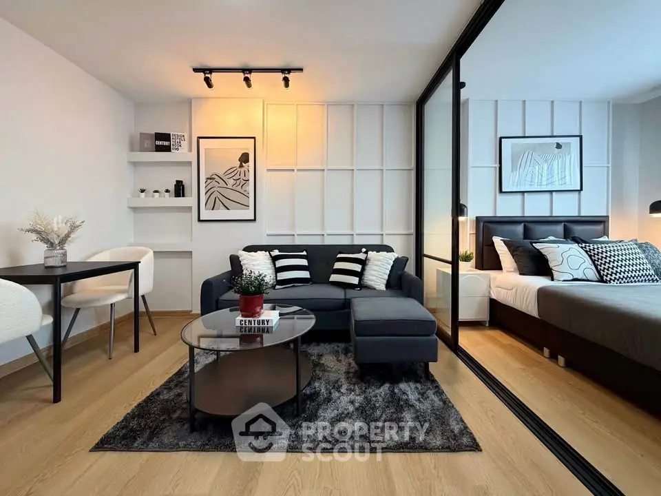 Modern living room with stylish decor and adjacent bedroom, featuring sleek furniture and elegant design.